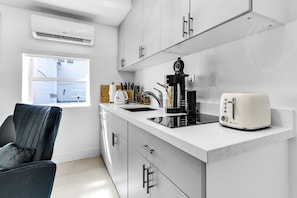 Una cucina moderna con mobili bianchi, un piano di lavoro nero, un tostapane e una macchina da caffè.