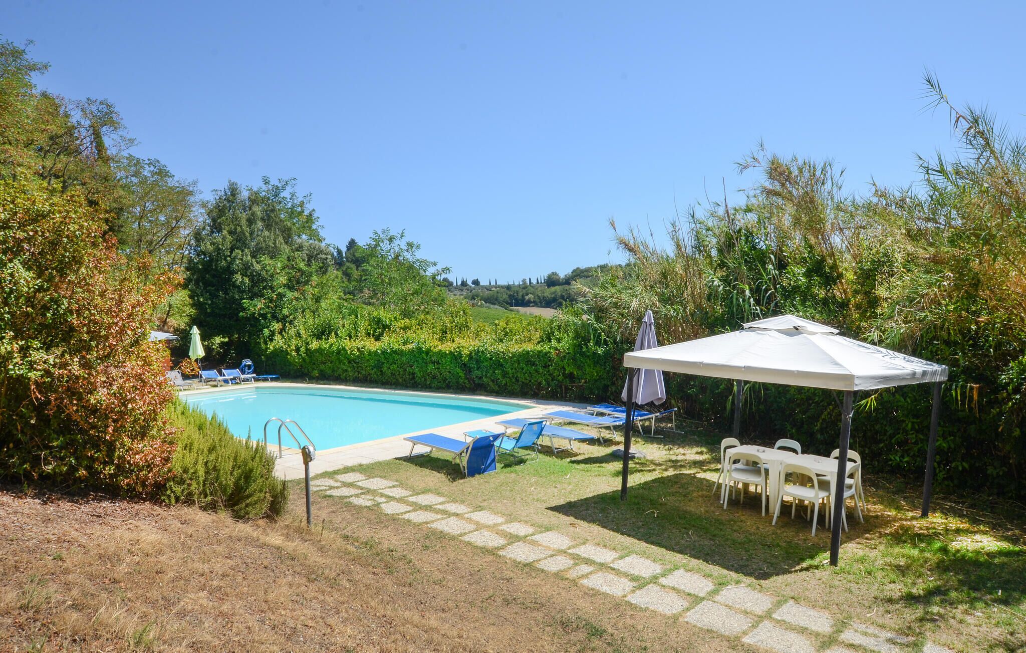 A swimming pool with lounge chairs and a covered seating area.