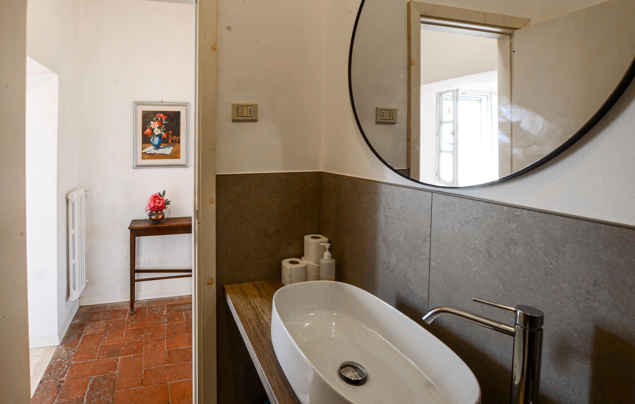 A bathroom with a white sink, a mirror, and a toilet paper dispenser.