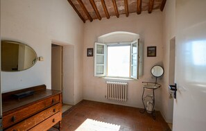 A room with a wooden dresser, a radiator, a window with shutters, and a small table with a mirror. - Cozy apartment in Poggibonsi with swimming pool (Poggibonsi)
