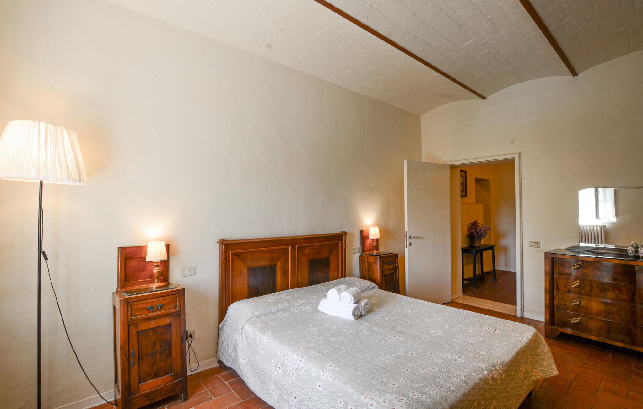 Ein Schlafzimmer mit einem Bett, Nachttischlampen, einem Schminktisch und einem Spiegel.