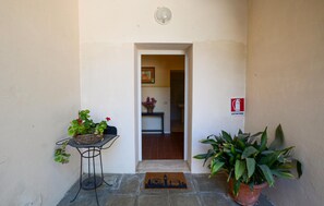 A doorway leading to a room with a fire extinguisher sign, a small table with a basket of flowers, and a potted plant. - Nice home in Poggibonsi with outdoor swimming pool (Poggibonsi)