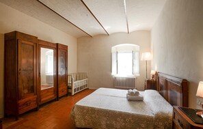 A bedroom with a large bed, wooden wardrobe, a crib, and a window with a view. - Nice home in Poggibonsi with outdoor swimming pool (Poggibonsi)