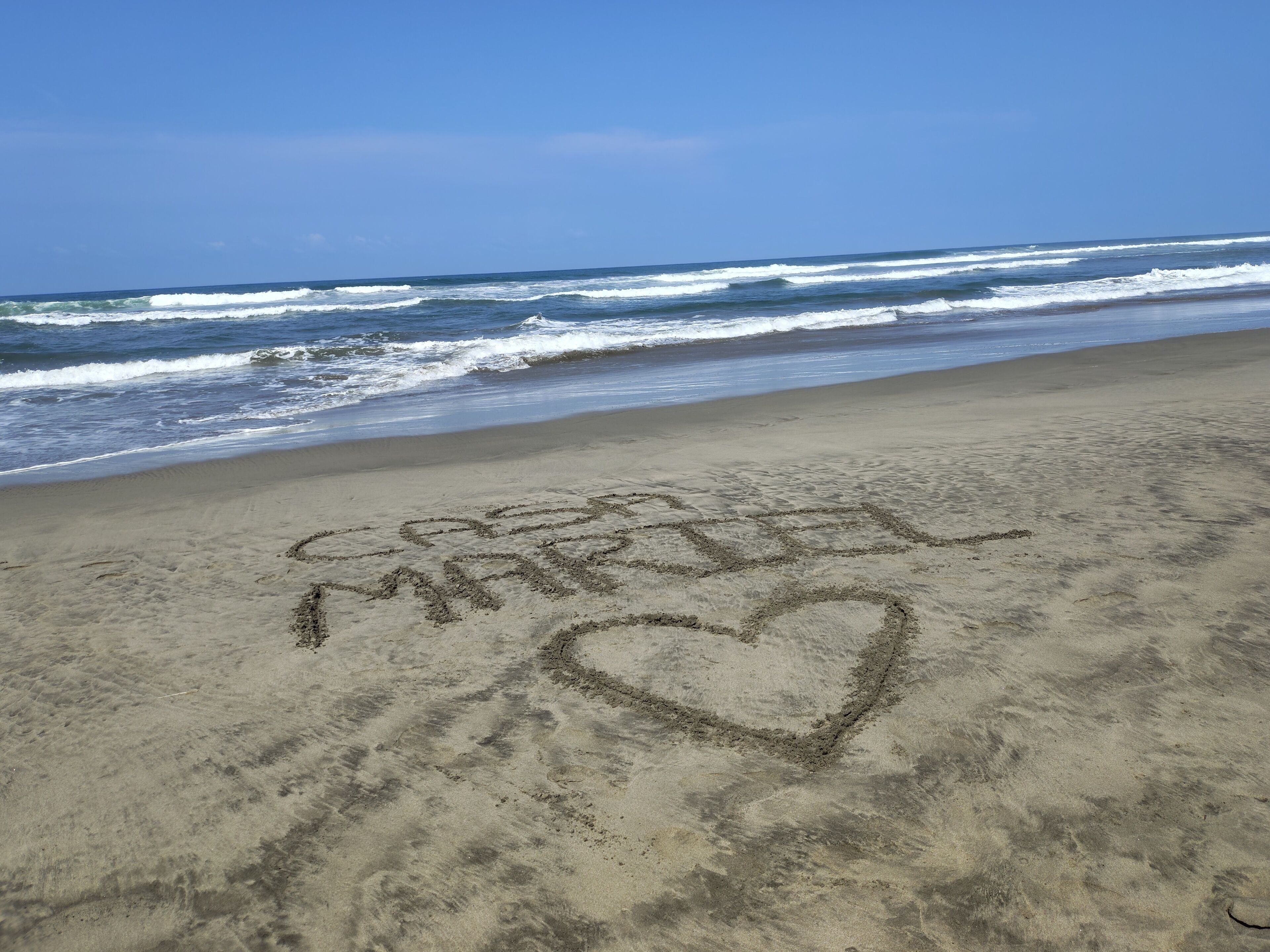 A beach with the words 'Love' and a heart drawn in the sand.