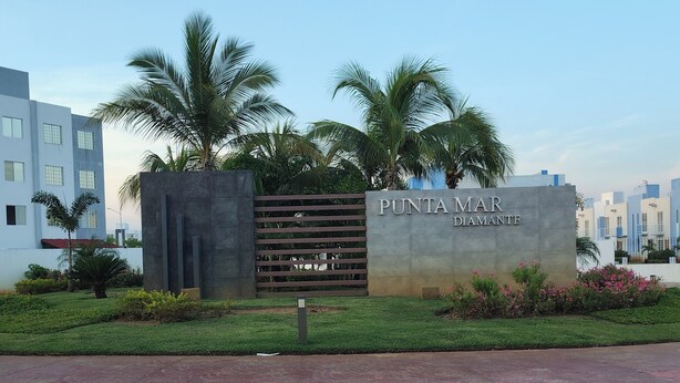 Een bordje voor Punta Mar Diamante, met een modern hek en palmbomen.