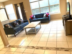 A living room with two sofas, a coffee table, and a TV on a stand. - 4BR Denton Home Near UNT & TWU--Perfect for Work Trips & Families (Texarkana)