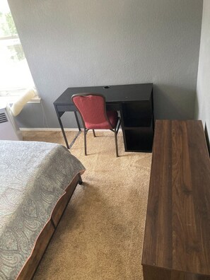 Une pièce comprenant un lit, un bureau, une chaise et une table en bois.