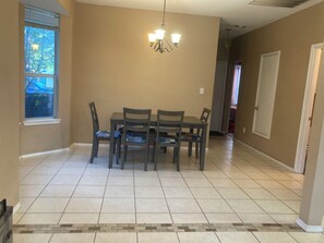 A dining area with a table and chairs, a chandelier, and a window. - 4BR Denton Home Near UNT & TWU--Perfect for Work Trips & Families (Texarkana)