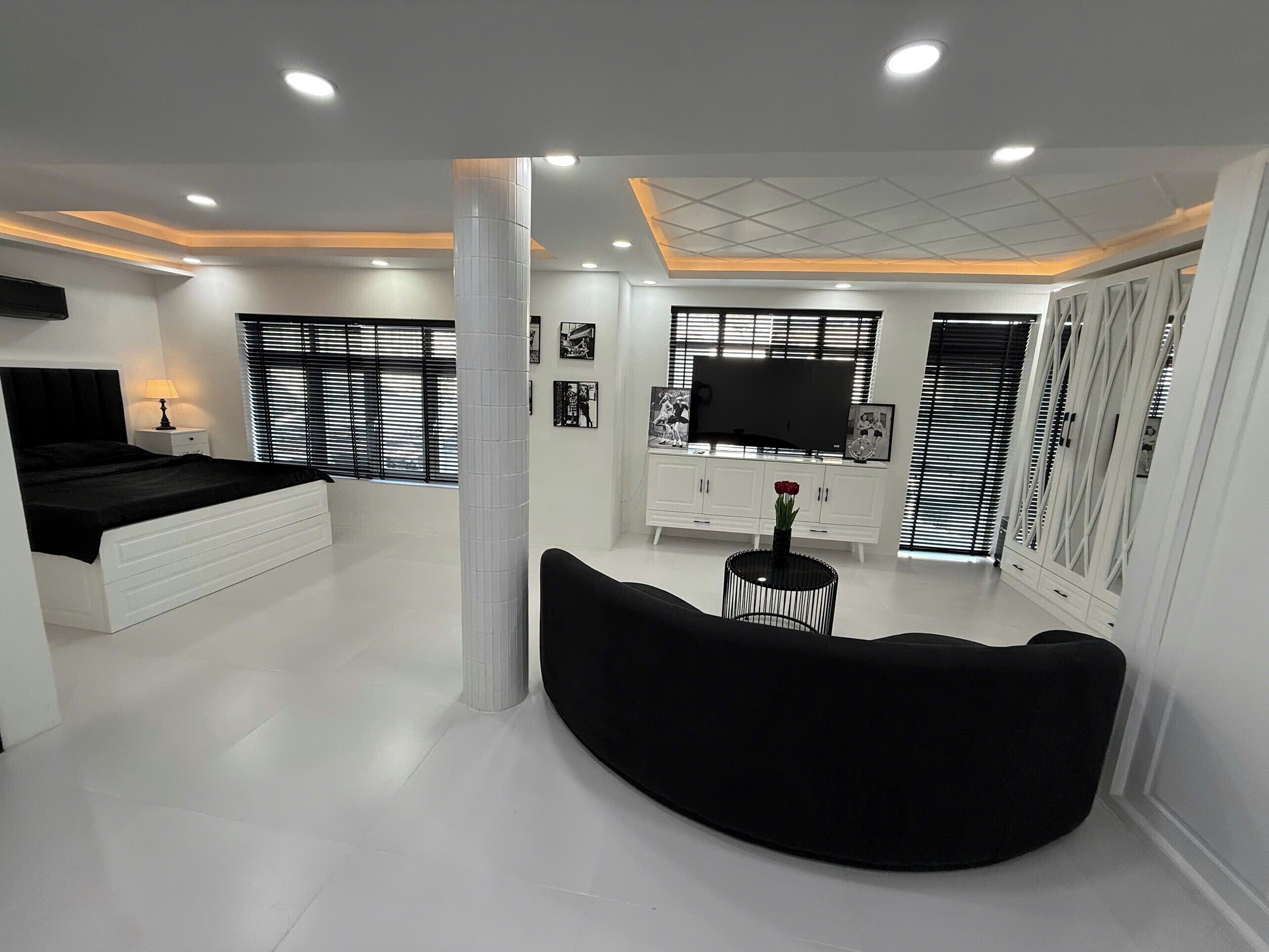 A modern bedroom with a bed, a TV, a sofa, and a white cabinet.