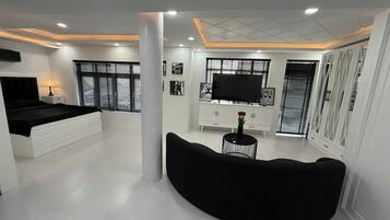 A modern bedroom with a bed, a TV, a sofa, and a white cabinet.