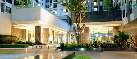 Un hotel moderno con un patio central, una fuente de agua y un árbol grande.