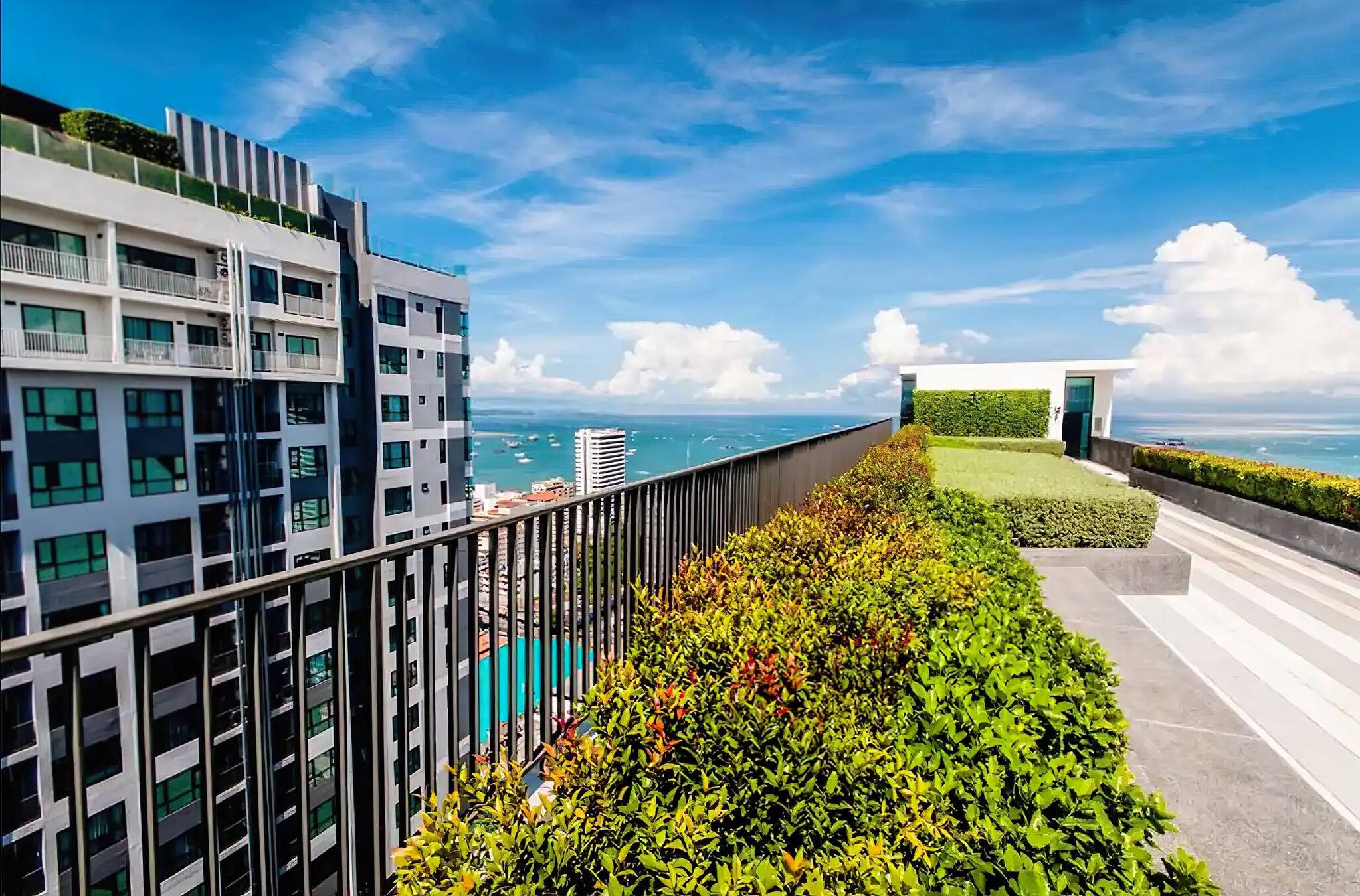 A modern building with a balcony overlooking a body of water and a clear sky.