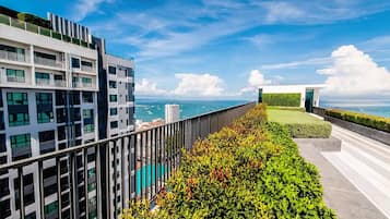 A modern building with a balcony overlooking a body of water and a clear sky.