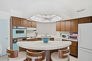 Eine Küche mit einem runden Tisch, Holzschränken und Küchengeräten im Retro-Stil.