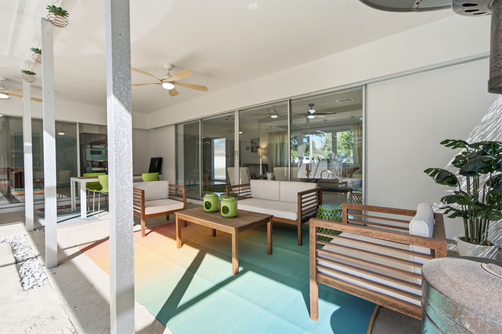 A modern living room with a sofa, coffee table, and chairs, a glass door leading to a balcony, and a ceiling fan.