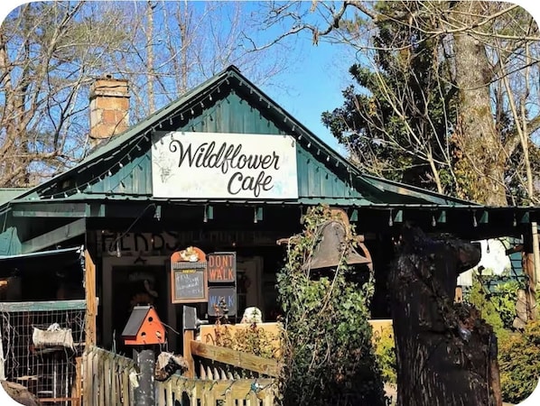 A rustic building with a green roof and a sign that reads 'Wildflower Cafe.'
