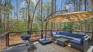 An outdoor deck with a barbecue grill, a large umbrella, and a sofa.