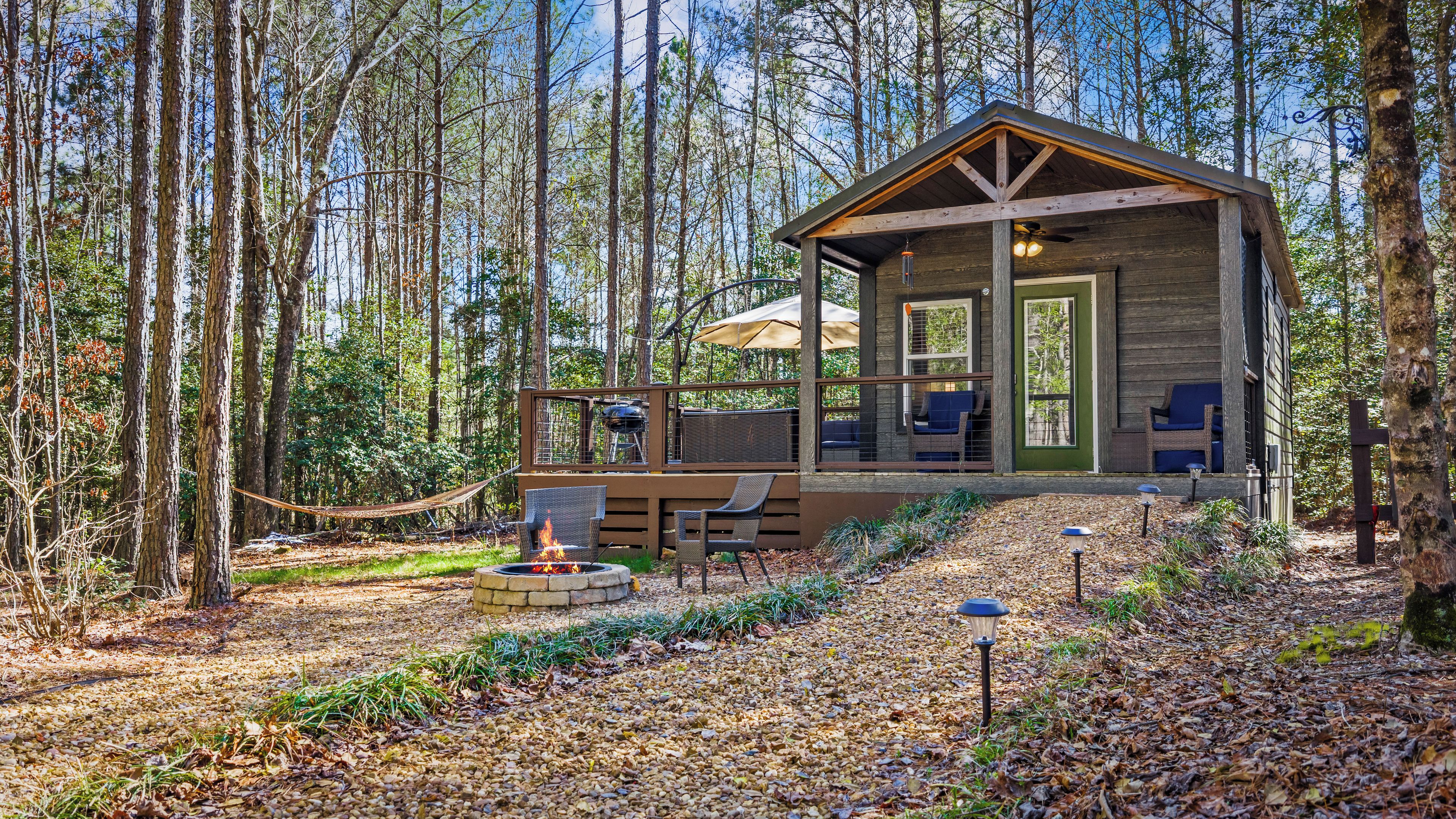 A cabin with a deck, outdoor seating, and a fire pit.