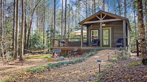 A cabin with a deck, outdoor seating, and a fire pit.