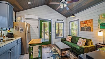 A compact kitchen with a refrigerator, sink, and a dining area with a table and bench.