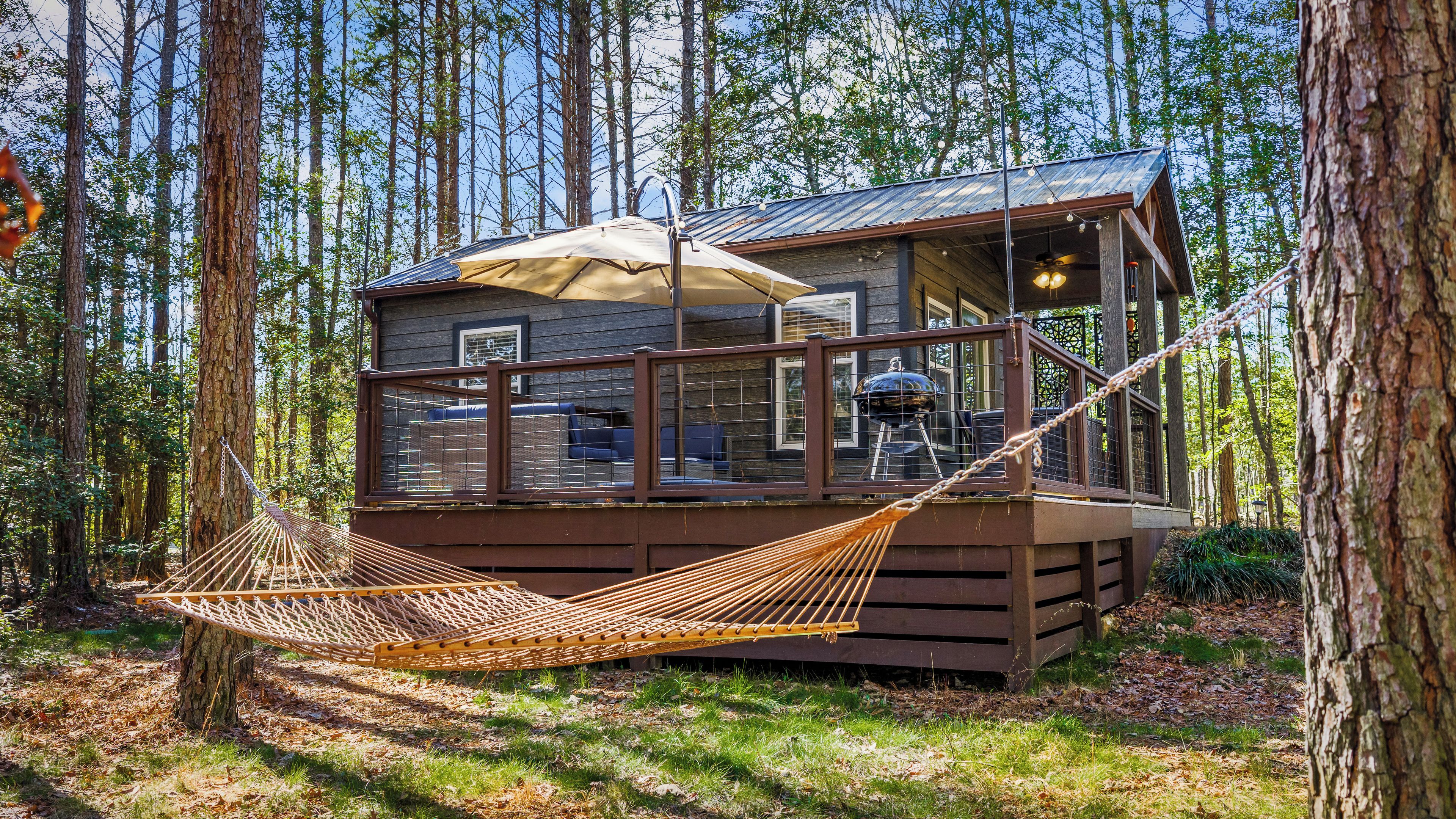 A cabin with a deck, a hammock, and a view of the forest.