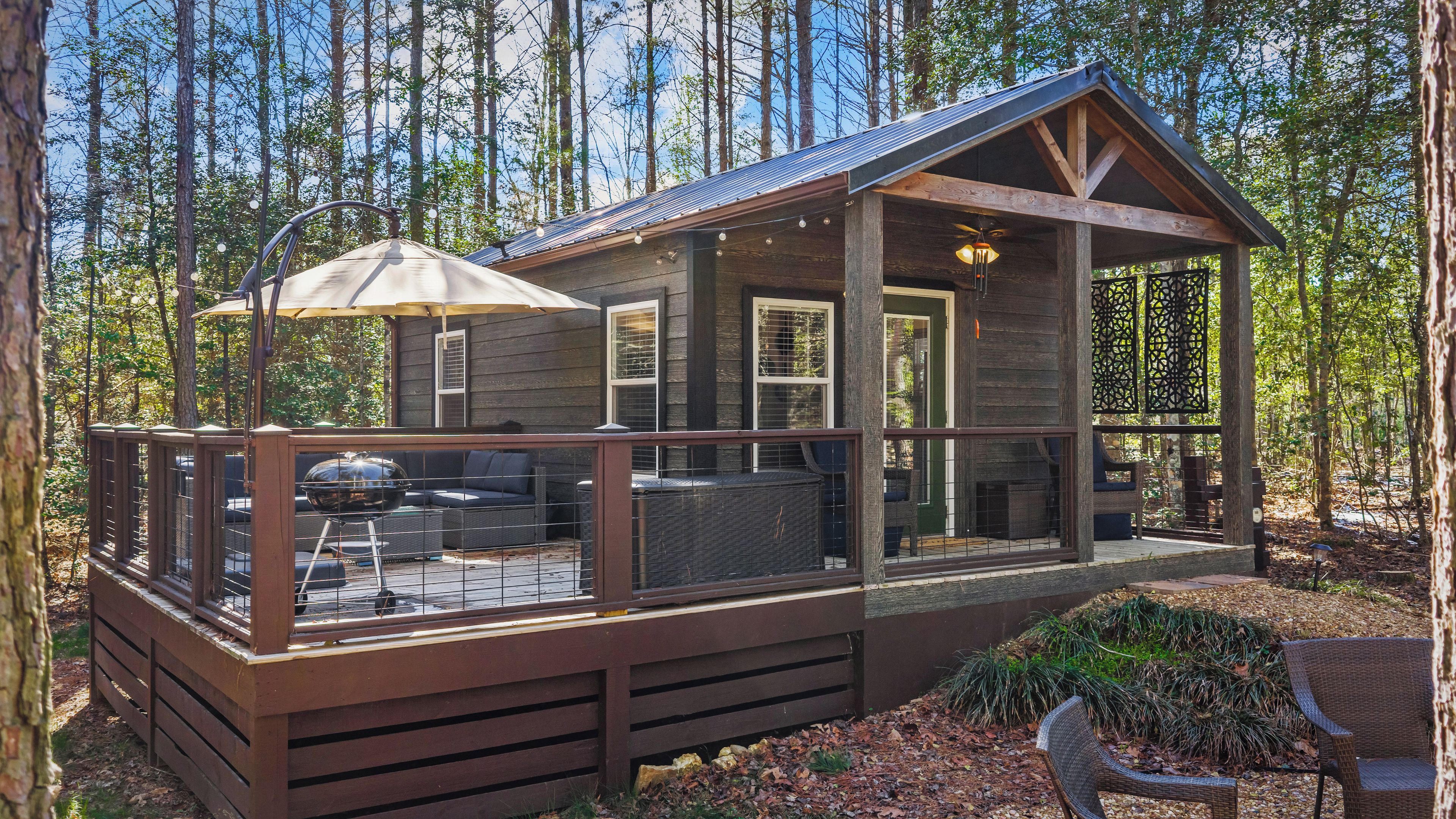Une cabane dotée d’une terrasse, de mobilier d’extérieur et d’un patio couvert.