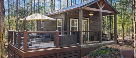 A cabin with a deck, outdoor furniture, and a covered patio area.