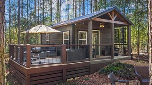 Una cabaña con terraza, mobiliario exterior y un patio cubierto.