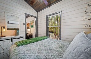 Een slaapkamer met een bed, een dresser, een spiegel en een raam met uitzicht.