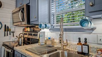 A modern kitchen with stainless steel appliances, a built-in oven, and a window with blinds.