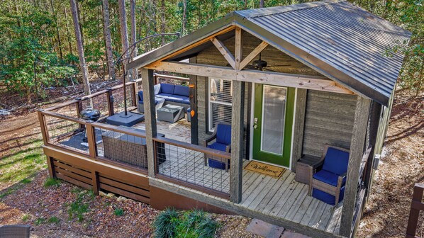 A wooden cabin with a deck, outdoor seating, and a green door.