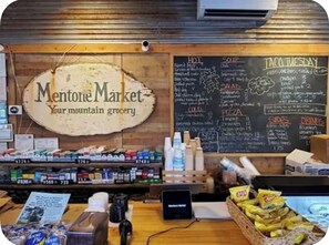 A grocery store interior with a sign reading 'Mentone Market Your mountain grocery.'