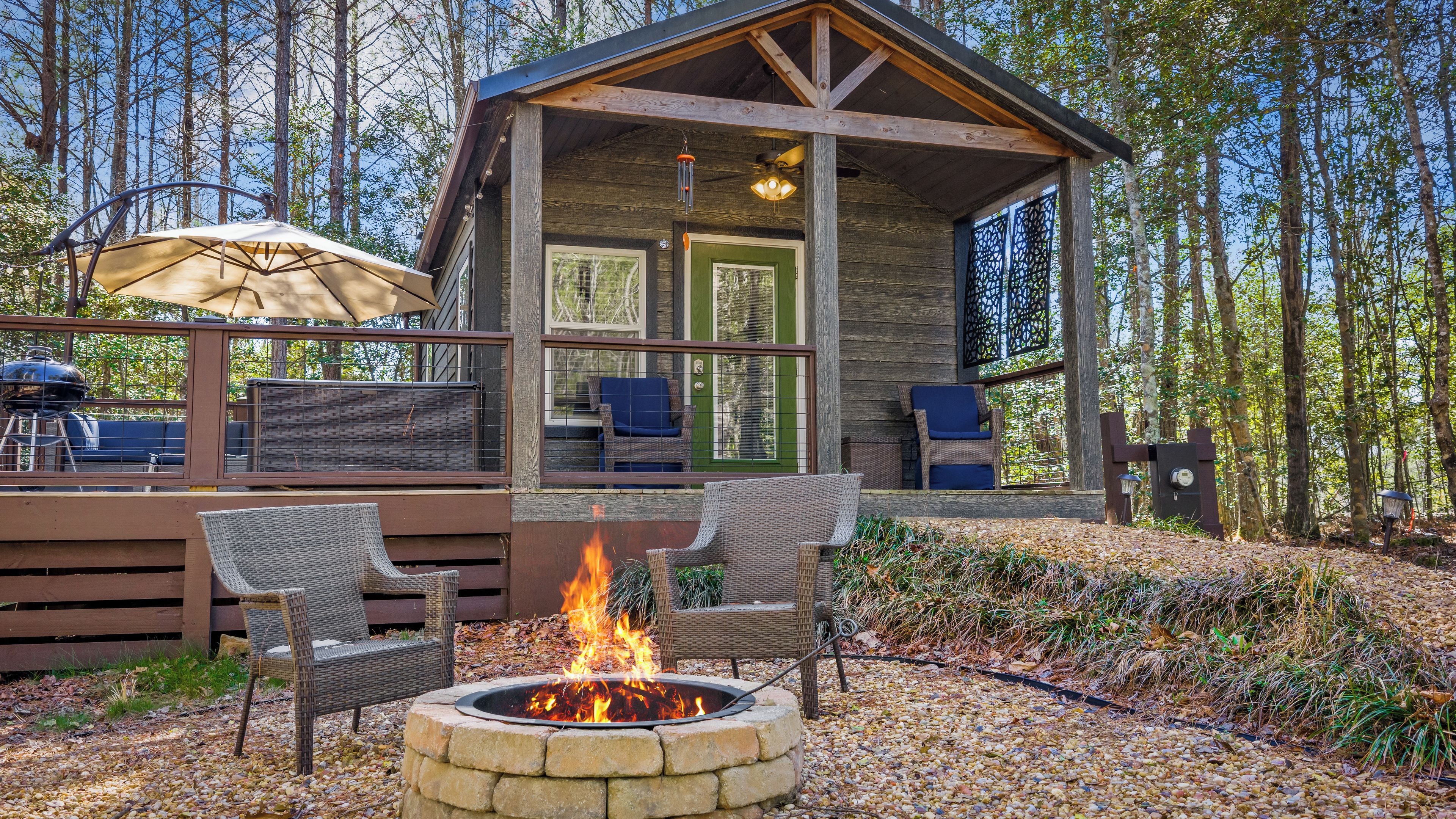 A cabin with a deck, outdoor seating, and a fire pit.