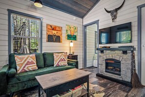 A cozy living room with a green sofa, a fireplace, and artwork on the walls.