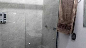 Un baño con cabina de ducha de vidrio, inodoro y lavamanos.