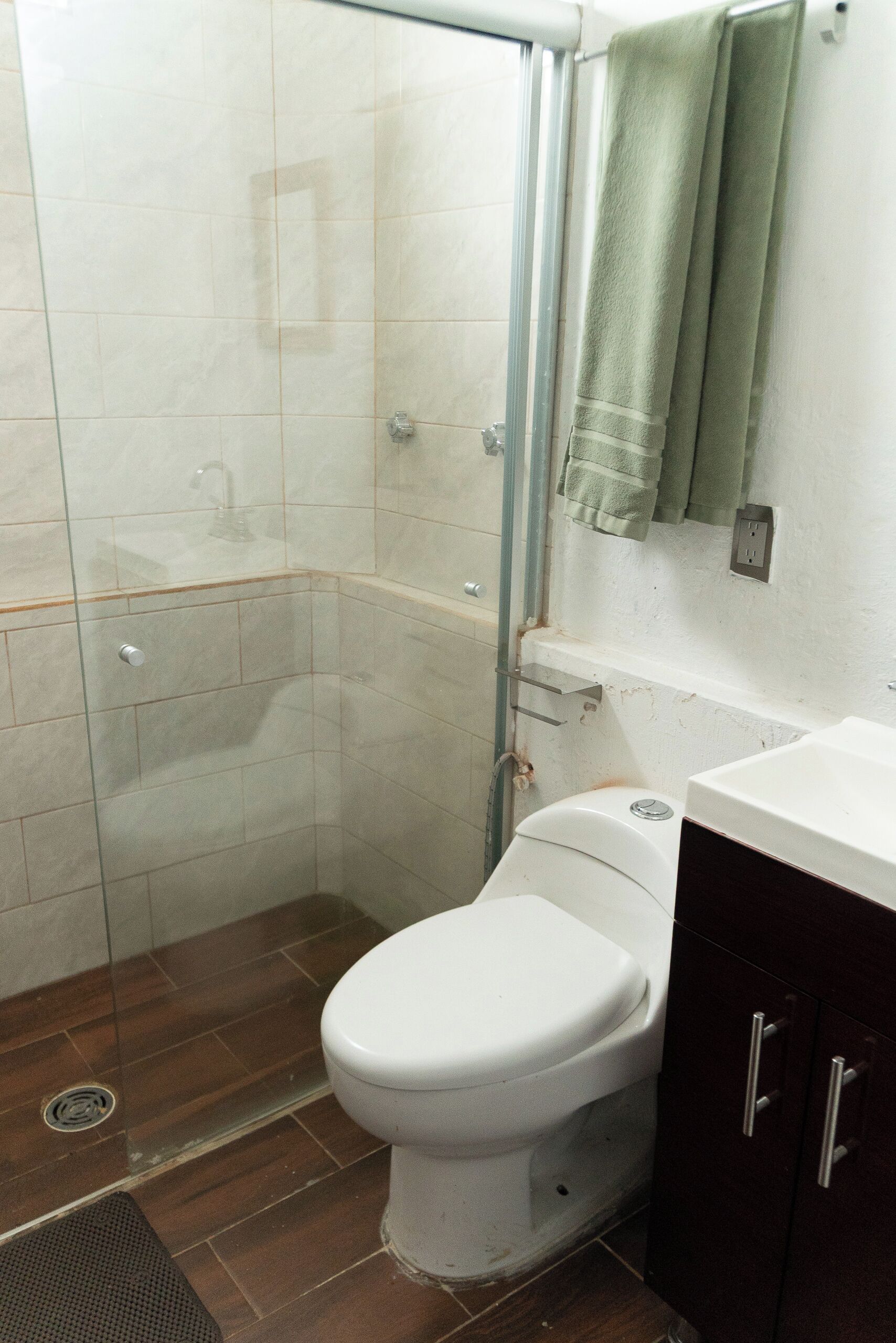 Une salle de bain équipée d’une douche, de toilettes et d’un miroir avec une serviette.