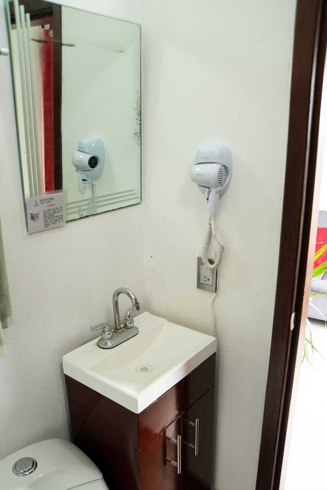 A bathroom with a white sink, a mirror, a hairdryer, and a towel rack.