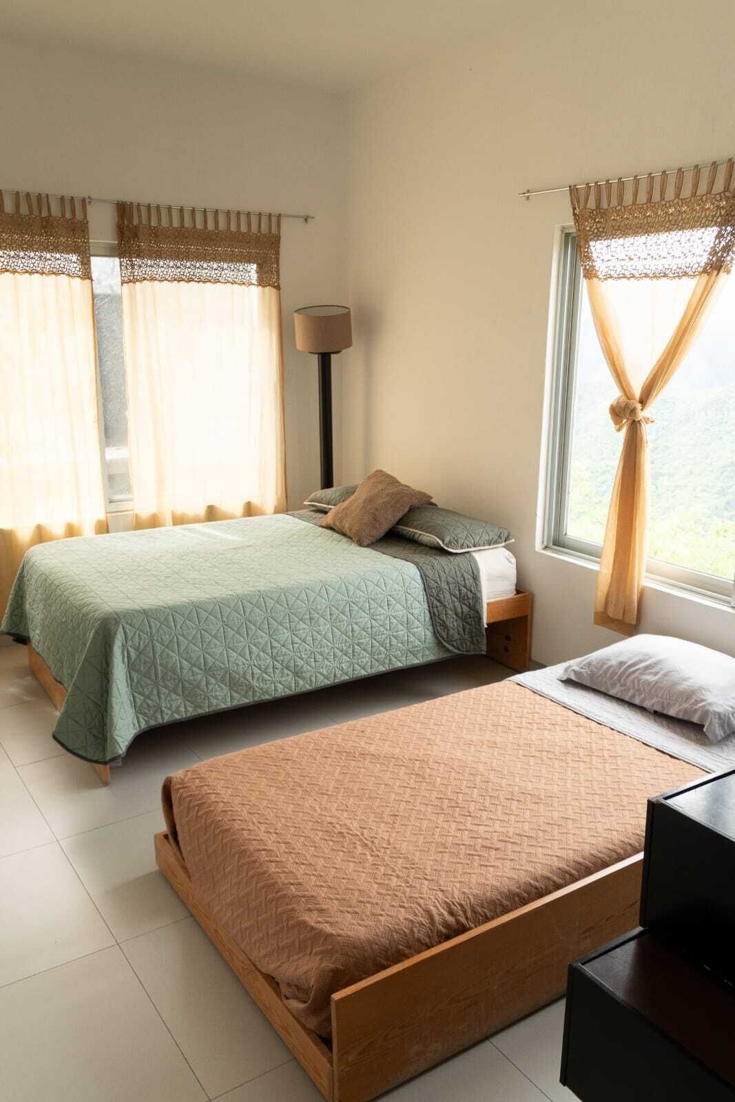 Une chambre avec deux lits, une lampe et une vue par la fenêtre.