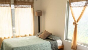 Een kamer met twee bedden, een lamp en uitzicht door het raam.