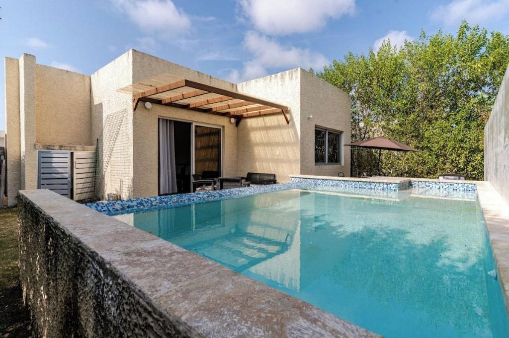 En modern utomhuspool med en pergola, en täckt sittplats och en uteplats med utemöbler.
