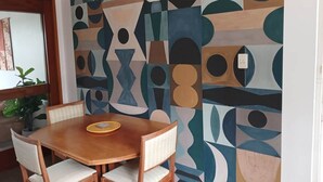 Ein Essbereich mit Holztisch und -stühlen, einer Wand mit Muster und einer Blumentopf-Pflanze.