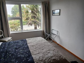 Una habitació d'hotel amb un llit, una finestra amb cortines, una cadira i un quadre a la paret.