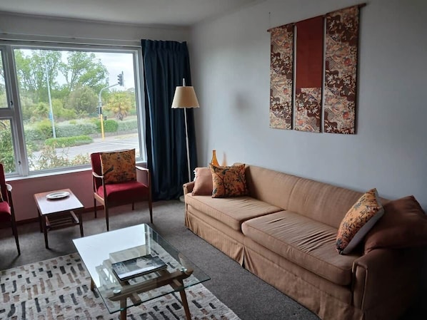 A living room with a sofa, armchair, coffee table, and a lamp.