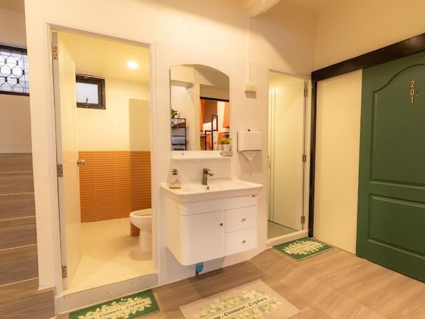 A bathroom with a white sink, mirror, and a green door. - Social Pod Khao San Hostel (Bangkok)