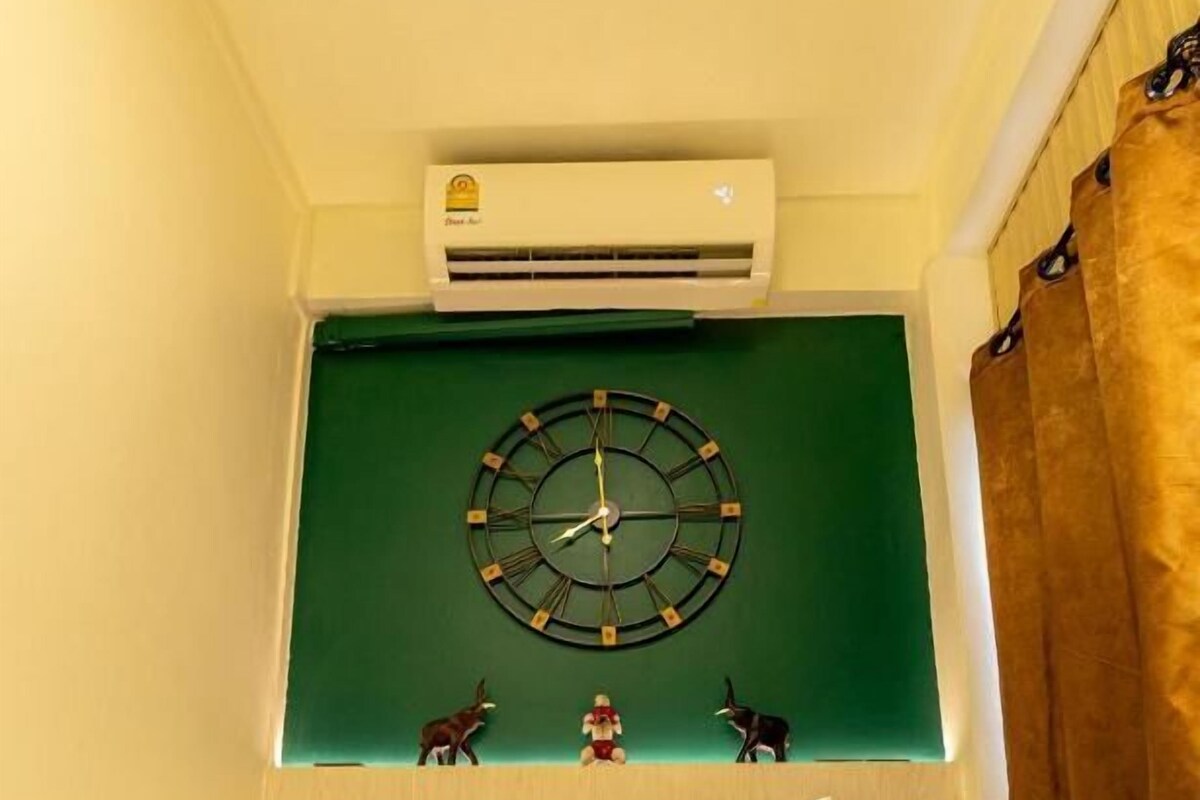 Ein Hotelzimmer mit Bett, Wanduhr und Klimaanlage.