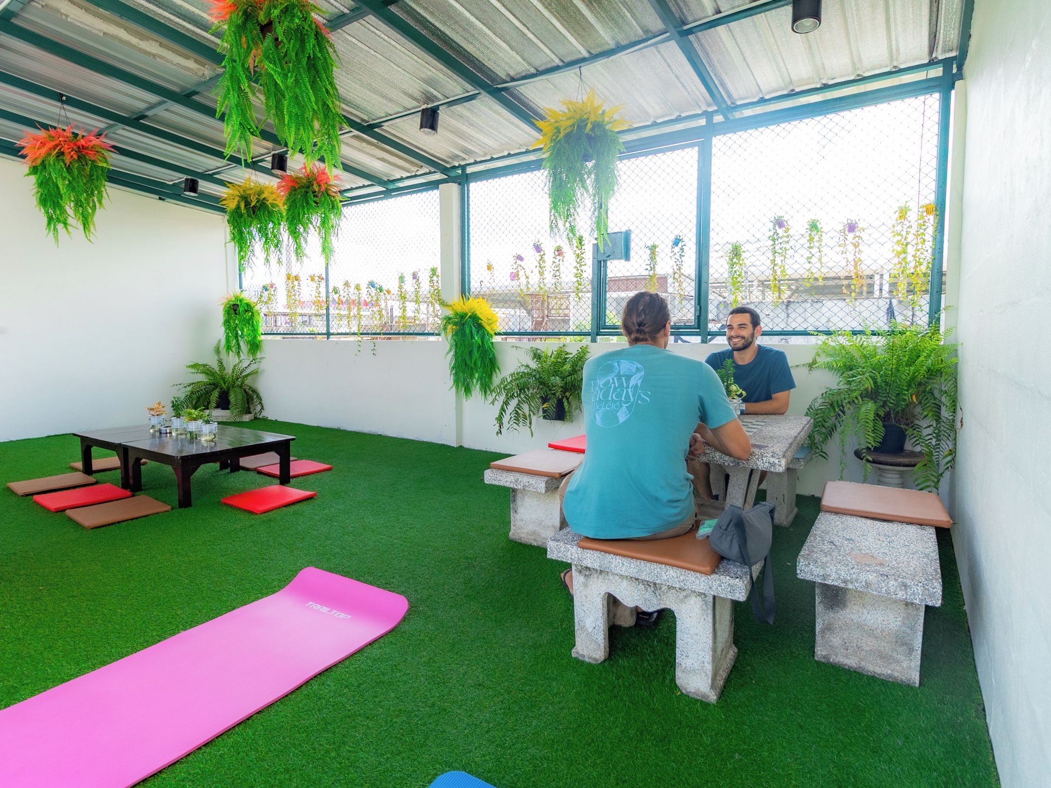 An indoor space with artificial grass, seating areas, and hanging plants.