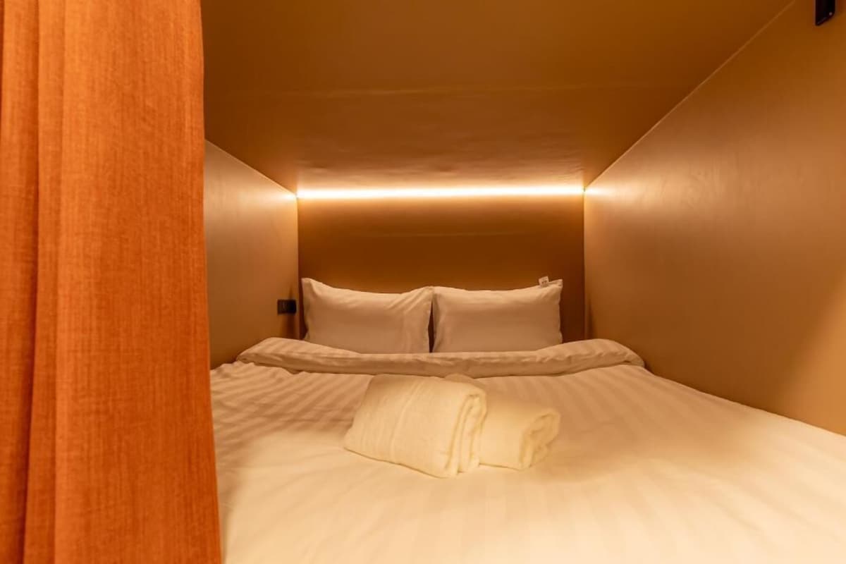A hotel room with a bed, pillows, and a folded towel.
