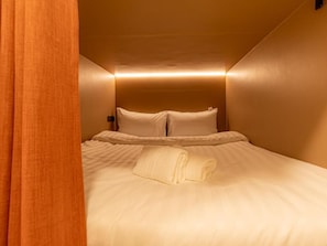 A hotel room with a bed, pillows, and a folded towel. - Social Pod Khao San Hostel (Bangkok)