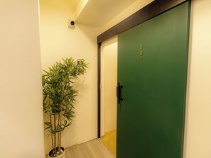 A hallway with a green door marked '501', a bamboo plant, and a small step leading to the door. -  Social Pod Khao San Hostel (Bangkok)