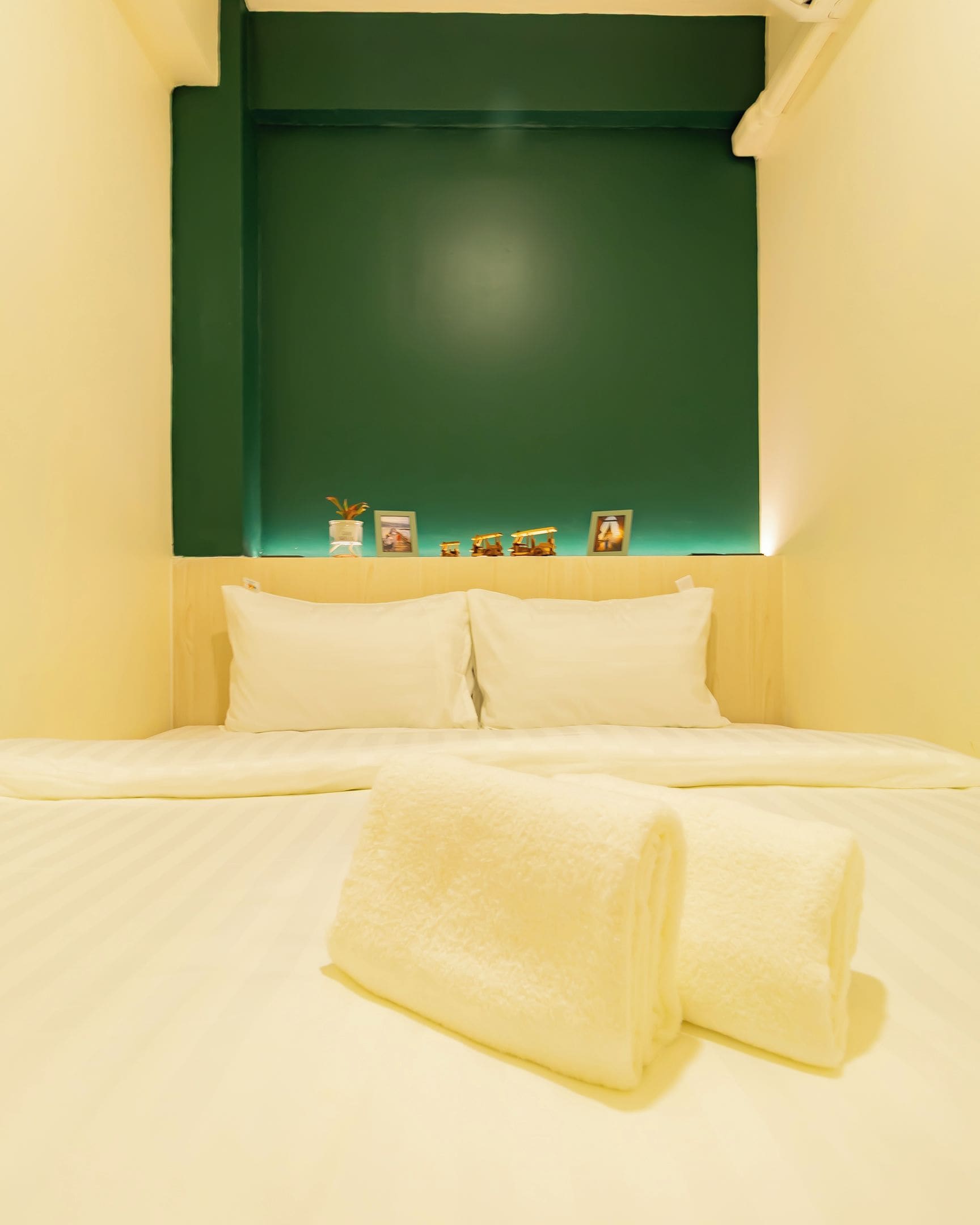 A hotel room with a bed, two pillows, and a headboard with a shelf displaying decorative items.